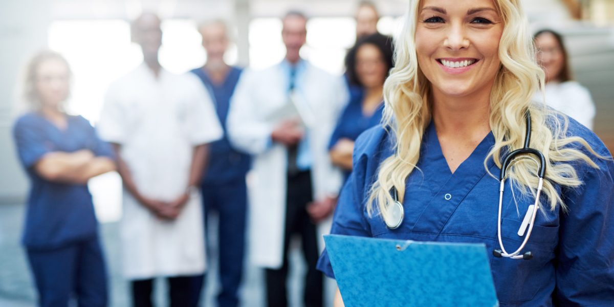 Female medical professional standing in a clinic and looking at camera. Team of doctors