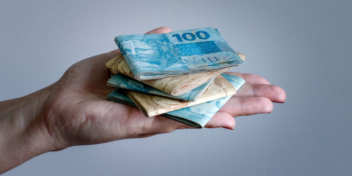 Hands holding Brazilian real notes, money from Brazil, notes of Real, Brazil BRL banknote, Brazilian currency, economy and business.